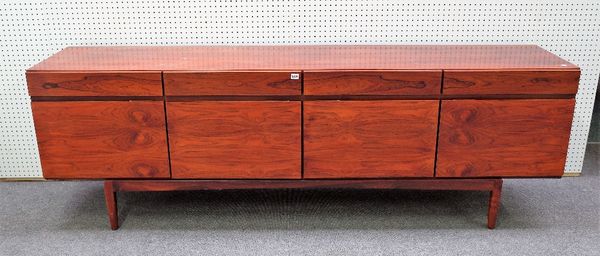 IS FAARUP MOBEL FABRIK, designed by Kofod Larsen, a 1960s rosewood sideboard with four drawers over two pairs of cupboards on tapering block supports,