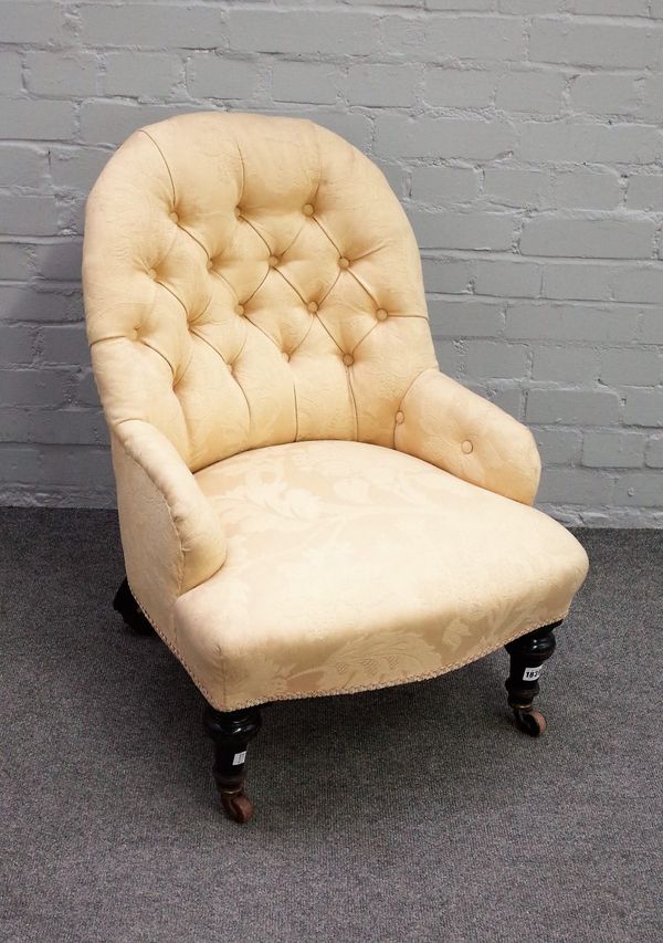 A Victorian button back nursing chair on turned ebonised supports, 55cm wide x 77cm high.