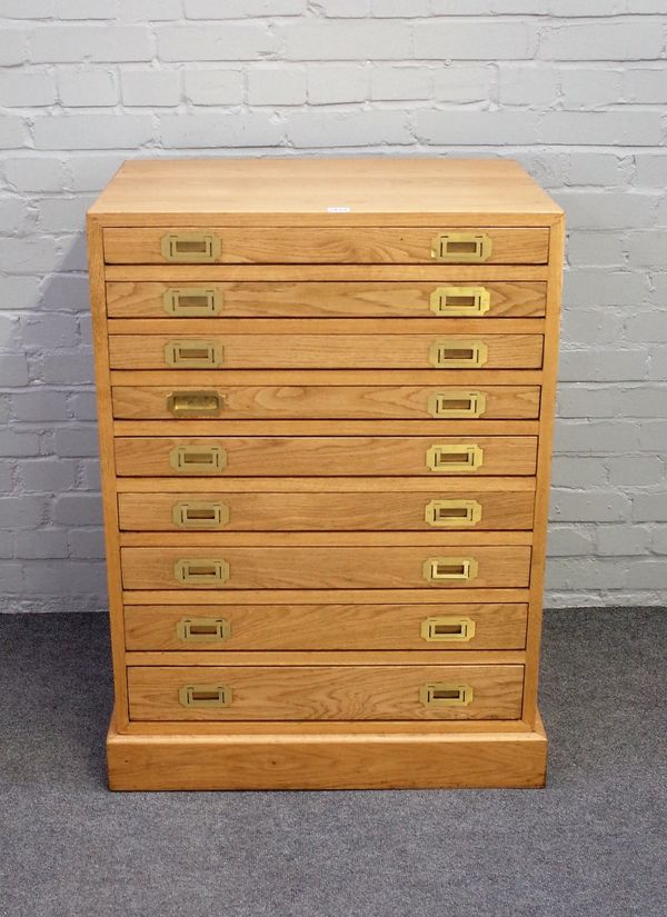 A 20th century light oak campaign style canteen chest with nine long graduated drawers on plinth base, 74cm wide x 99cm high.