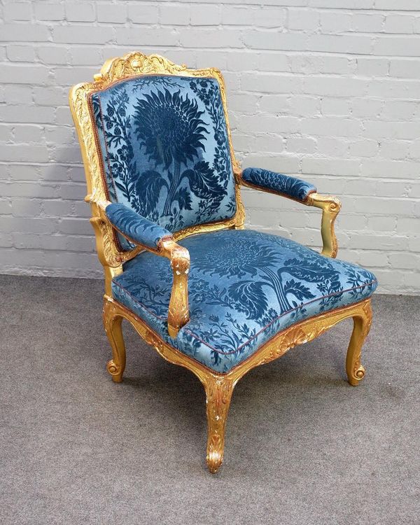 An 18th century French gilt framed open armchair/ fauteuil, with acanthus carved scrolling frame above concave seat and scroll supports, 101cm high x