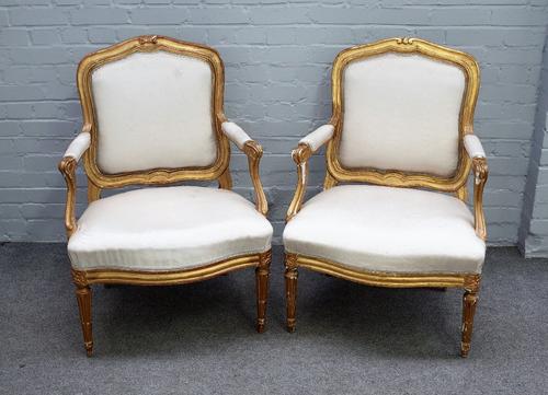 C Chevigny; a pair of Louis XVI gilt framed open armchairs, with serpentine seats, on tapering fluted supports, 70cm wide x 98cm high, (2).