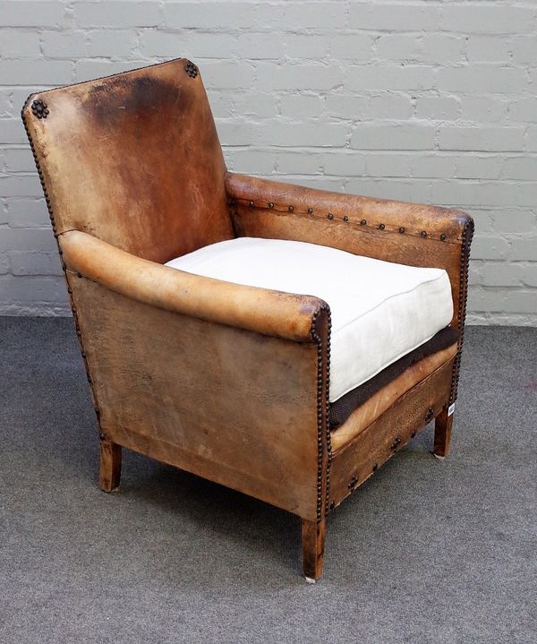 An early 20th century studded brown leather upholstered easy armchair on tapering block supports, 62cm wide x 82cm high.