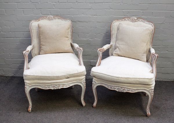 A pair of Louis XV style open armchairs with distressed white painted frames, 70cm wide x 92cm high.