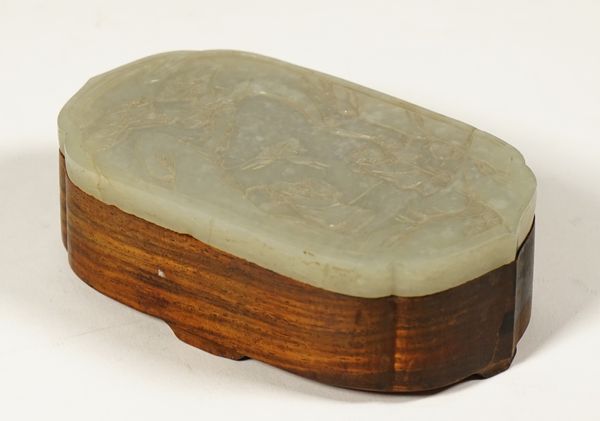 A Chinese hardwood box with jade cover, late 19th/20th century, of shaped oblong form, the thinly carved jade of pale celadon tone, carved with two fi