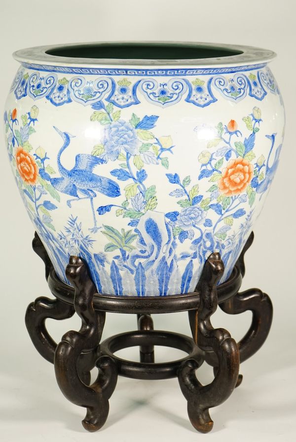 A large Chinese porcelain polychrome jardiniere, modern, decorated with storks amongst flowering shrubs, 41cm. high, wood stand, (2).