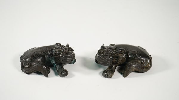 A pair of Chinese bronze figures of Buddhist lions, 19th century, each cast in recumbent pose facing to the left or right, each 10cm. length, (2).