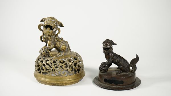 A Chinese bronze cover, Ming dynasty, 17th century, surmountewd by a Buddhist lion, seated with one paw resting on a brocade ball, 15cm. high; and a l