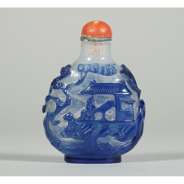 A Chinese blue overlay glass snuff bottle, 19th century, one side carved with a figure seated beside a teapot in a landscape, the reverse with two fig