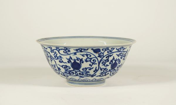 A Chinese porcelain blue and white bowl, Wanli six character mark but later, painted with fruit and tendrils above a ruyi head border, 21.5cm. diamete