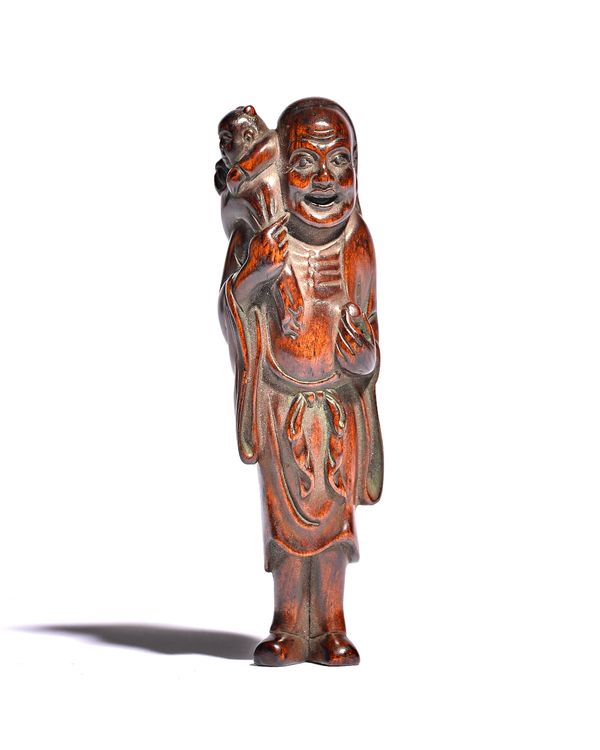 A Japanese wood netsuke of a sennin, 19th century, carved standing carrying a child across his right shoulder, unsigned,9.5cm. high. 10