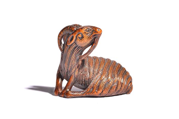 A Japanese wood netsuke of a recumbent goat, 19th century, carved with head turned across its back, unsigned, 4.25cm. length. 30