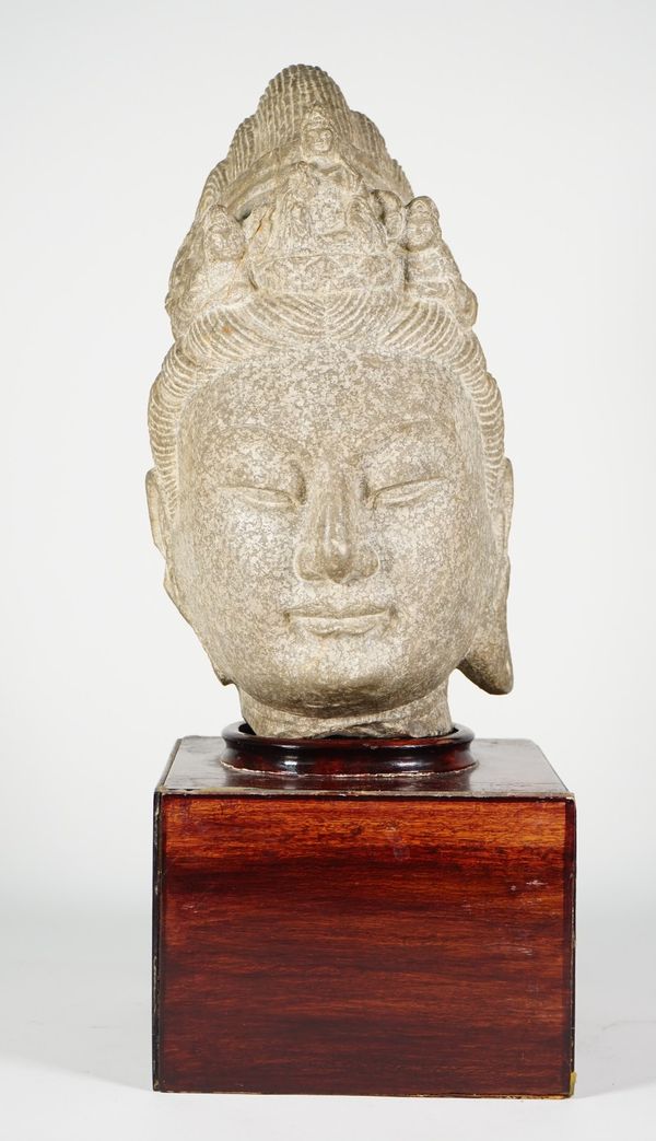 A Chinese stone head of Buddha, possibly Ming dynasty, carved wearing a serene expression, her crown carved with a small central figure of amitabha Bu