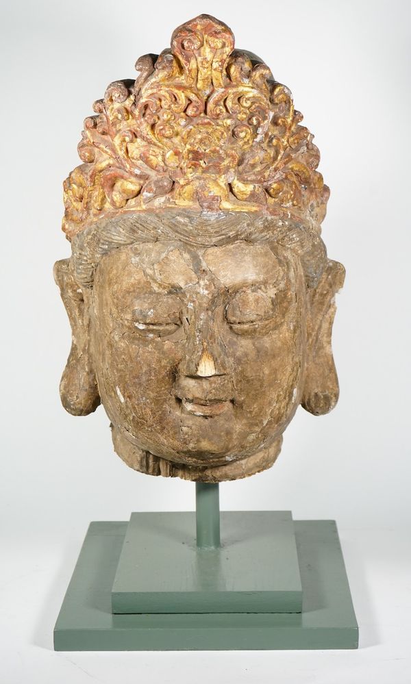 A large painted and parcel giltwood head of Guanyin, carved with serene expression and wearing a foliate tiara, 52cm. high, with stand.