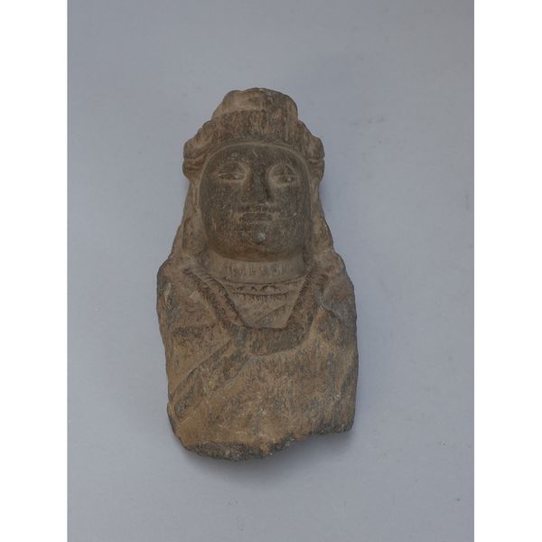 A small Gandhara sandstone bust of Buddha, 3rd/4th century, wearing a headress and with eyes closed in meditation, 20cm. high.