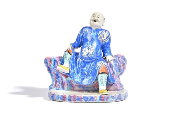 A rare Chinese famille-rose group, Qianlong, modelled as an open mouthed man seated on rockwork, wearing a blue robe with dragon medallions, (a.f), 20