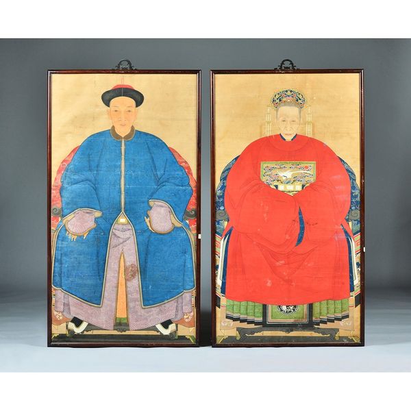 A pair of Chinese ancestor portraits, 19th century, ink and colour on paper, the man wearing a blue surcoat and hat, the woman with a red surcoat with