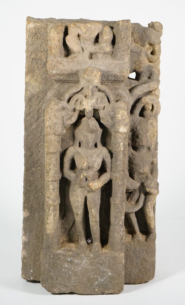 An Indian stone fragment, 11th century, carved with Parvati standing in a niche, another figure to her left, (a.f), 45cm. high.