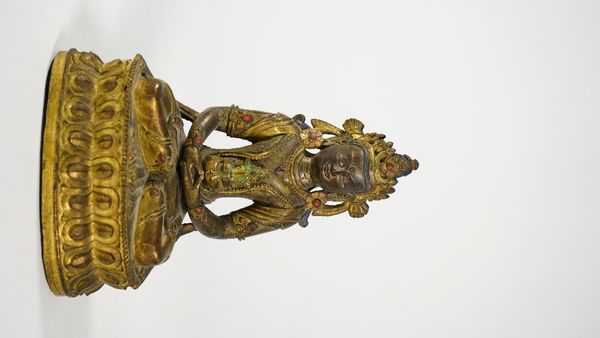 A gilt-brass figure of Buddha, probably 20th century, cast seated on a double lotus base holding a vase of flowers, 19cm. high.