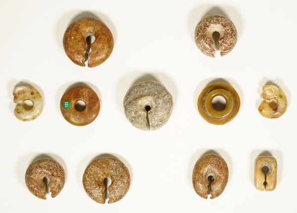 A group of Chinese archaistic jades, various colours, comprising; seven slit rings, jue, largest 6cm. wide; two zhulong, largest 4cm. wide; a disc and