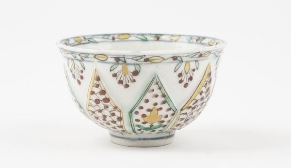 A Kutahya type teabowl, 18th century or later, the sides moulded with lappets painted with flowers alternating with a scale pattern, foliate border, (