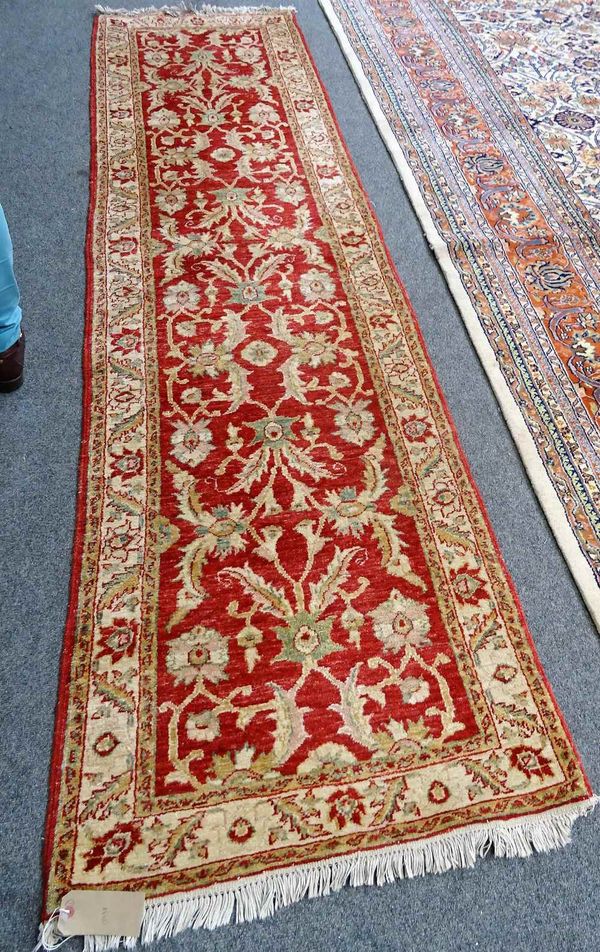 A Turkish runner, the madder field with a palmette, acanthus leaf and flower vine design, an ivory palmette and leaf border, 300cm x 81cm.  E3