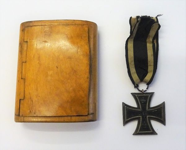 A German First World War period Iron Cross, second class and a curved rectangular treen cigarette box, detailed within Oberlieutenant Hans Orca Wurtsd