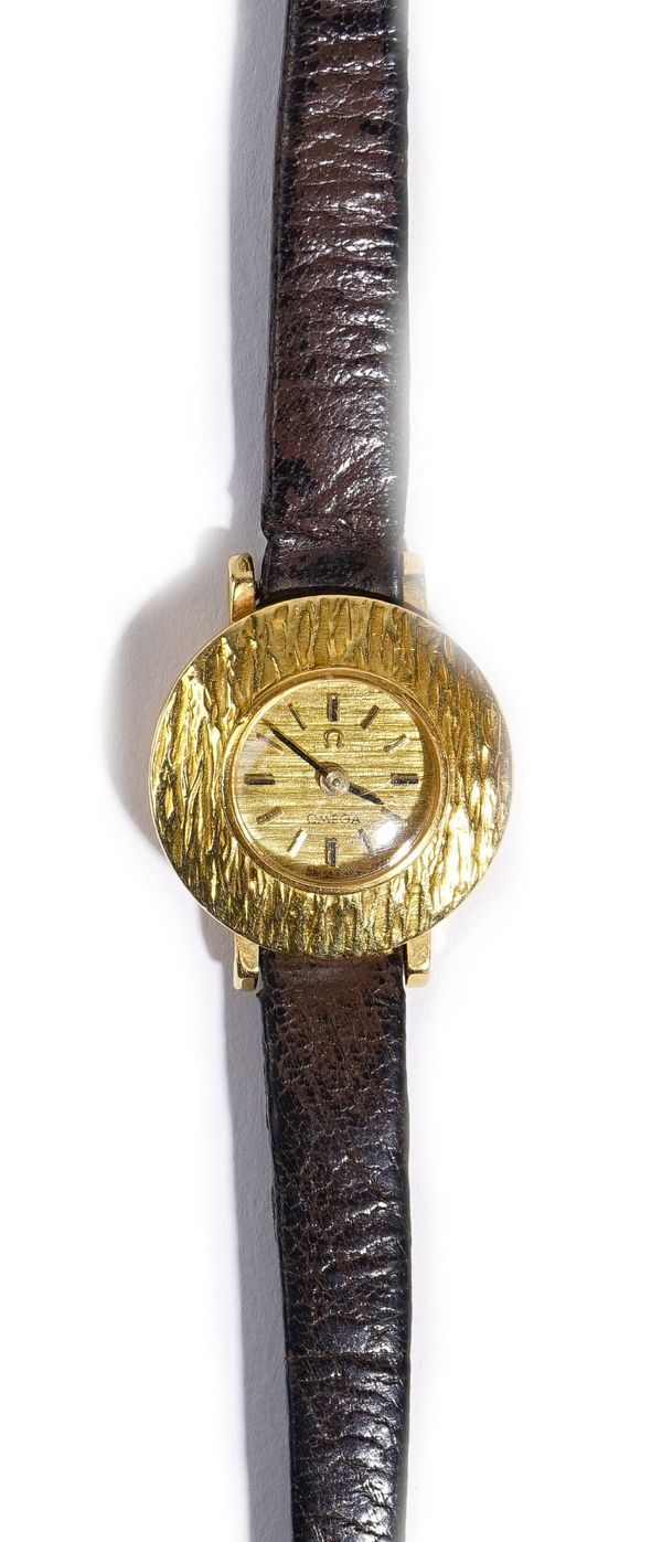 An Omega 18ct gold, circular cased rear winding lady's wristwatch, the signed textured dial with baton numerals and with black hands, the case front w