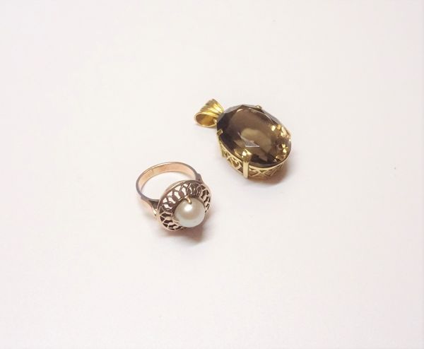 A gold ring, mounted with a cultured pearl within a pierced surround, ring size I and a half and a gold pendant, claw set with an oval cut smoky quart