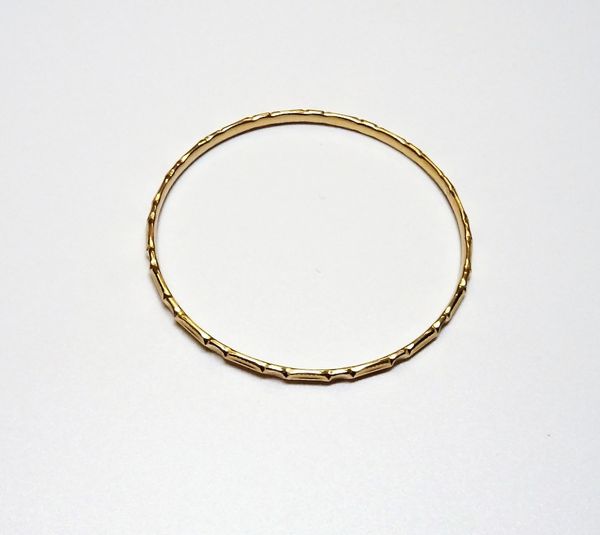 A gold circular bangle, with faceted decoration, weight 9.3 gms.