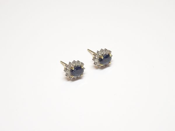 A pair of 18ct yellow and white gold, sapphire and diamond oval cluster earstuds, each claw set with an oval cut sapphire in a surround of circular cu