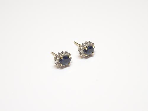 A pair of 18ct yellow and white gold, sapphire and diamond oval cluster earstuds, each claw set with an oval cut sapphire in a surround of circular cu