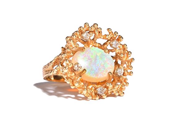 A gold, opal and diamond ring, claw set with the oval opal at the centre, in a surround of five circular cut diamonds, the mount with cast and pierced