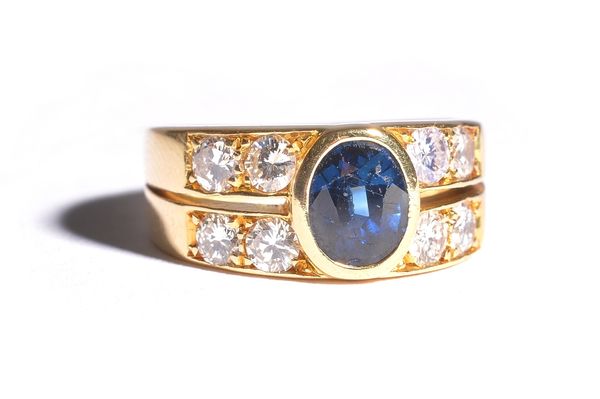 A gold, sapphire and diamond ring, collet set with the oval cut sapphire to the centre and with two pairs of circular cut diamonds mounted to each sid