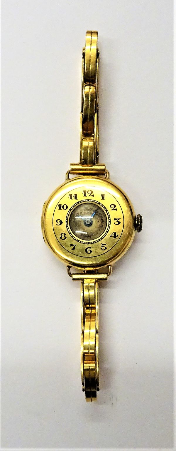 An 18ct gold circular half hunting cased lady's wristwatch, with a jewelled movement, the case front with black enamelled Arabic numerals, detailed wi