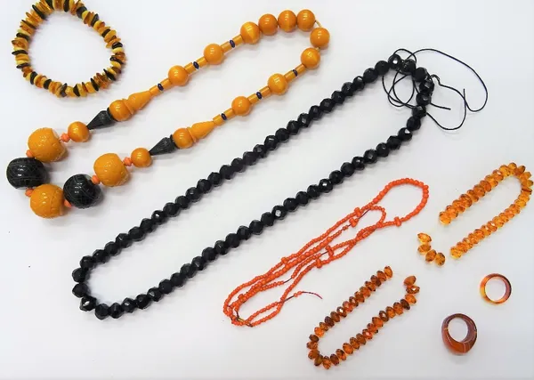 A coral bead necklace, two further bead necklaces, three reconstituted amber bracelets, a gold topped and rose diamond set stick pin, detailed 15 CT,