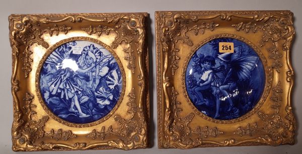 A pair of blue and white ceramic panels, depicting flower faries, each panel 17cm diameter.   ROST