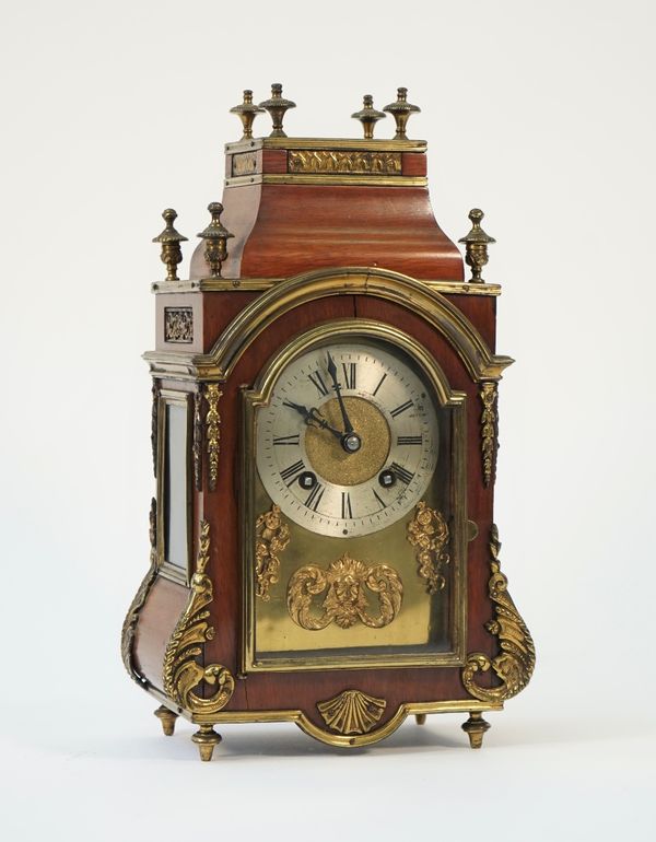 A French mahogany cased mantel clock, circa. 1900, with gilt metal finials and foliate embellishments, enclosing a two train movement of four turned f