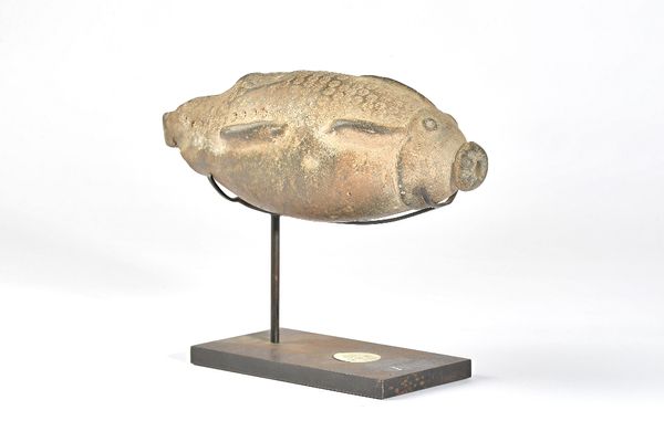 An unglazed pottery fish, possibly Persian, with impressed foliate decoration to back, on a later metal stand, fish 21cm, (a.f.). Illustrated.