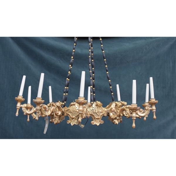 An Italian giltwood ten light corona chandelier, the foliate carved corona issuing ten swan neck branches, suspended by four wooden linked chains and