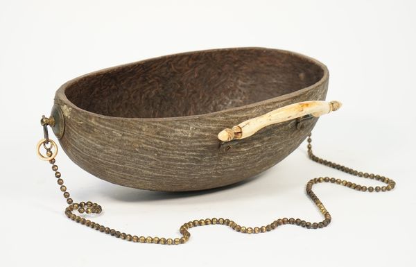 A 'Sufi' Indian begging bowl, 19th century, Coco De Mer portion, gilt metal mounts and a carved ivory handle, 32cm wide.