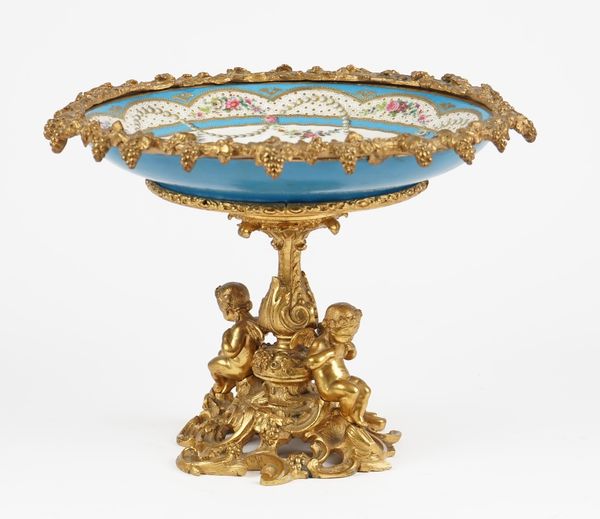 An ormolu and sevres style porcelain mounted comport, late 19th/early 20th century, the dish painted with a young girl reading a book against a landsc