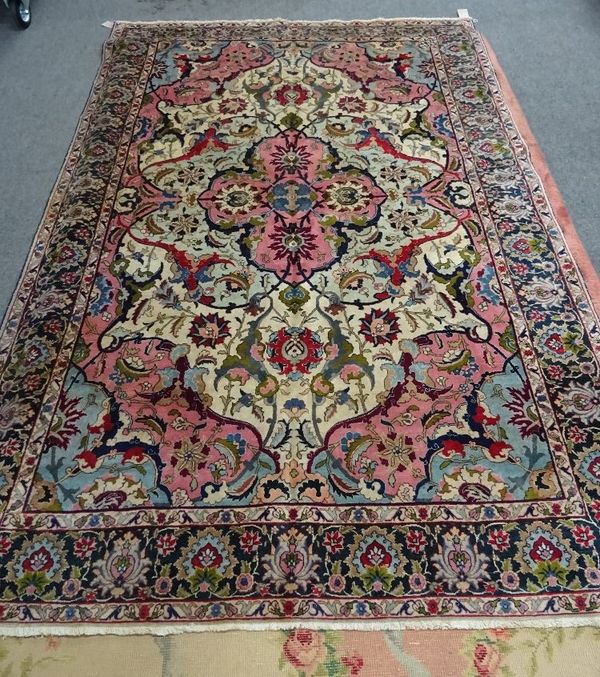 A Tabriz carpet, Persian, the ivory field with a pink medallion, with four palmettes, matching spandrels, all with bold vines and palmettes, a dark in