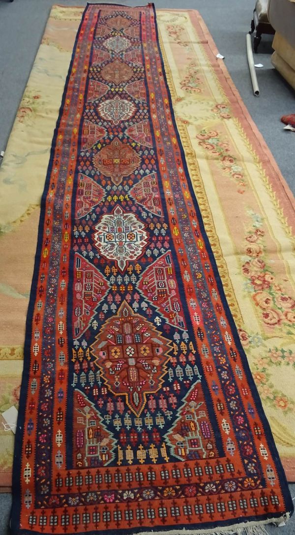 A Turkish flatweave runner, the dark indigo field with seven medallions half medallions, all with minor motifs, three borders, 576cm x 88cm.