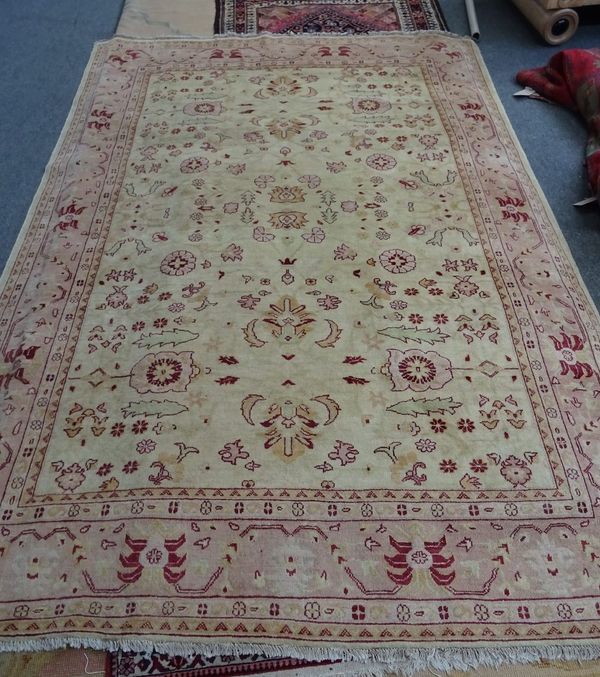 A Turkish carpet, the golden field with an allover floral design, pale pink border with palmettes and vines, 295cm x 216cm.