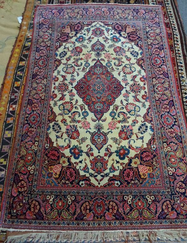 A Kashan rug, Persian, the ivory field with a madder diamond, matching spandrels, floral sprays, a complementary indigo border, 200cm x 131cm.