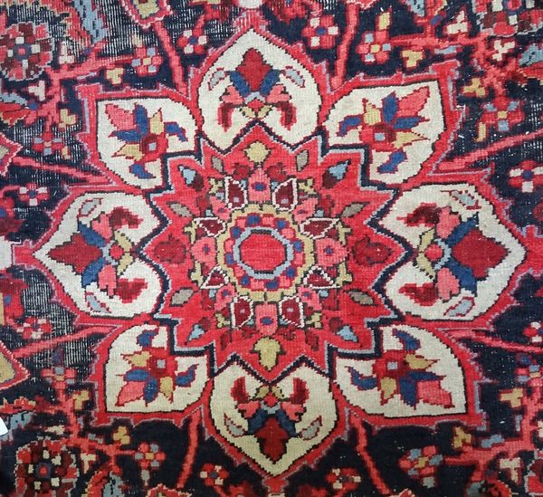 An antique Tabriz carpet with a lobed medallion and all over floral design on a red ground, unusual broad main border, approximately 422cm x 303cm.