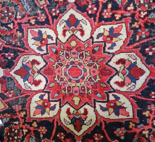 An antique Tabriz carpet with a lobed medallion and all over floral design on a red ground, unusual broad main border, approximately 422cm x 303cm.