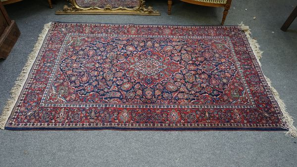 A Kashan rug, Persian, the indigo field with a madder medallion, matching spandrels, all with intricate floral sprays, a madder palmette and vine bord