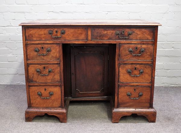 A George III mahogany kneehole desk with eight drawers about the cupboard on bracket feet, 100cm wide x 76cm high.