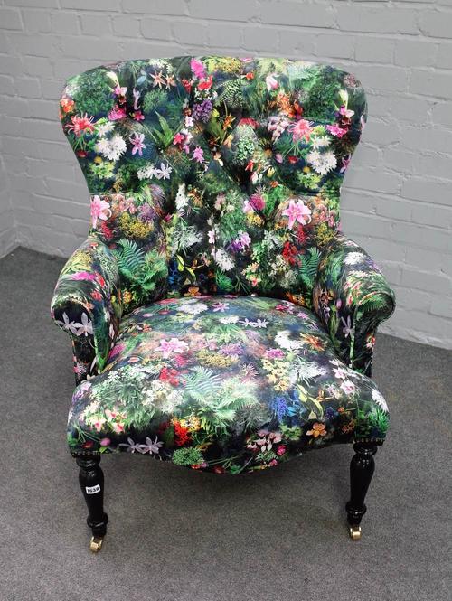 A Victorian style button back armchair, with floral pattern upholstery, on turned ebonised supports, 75cm wide x 105cm high.